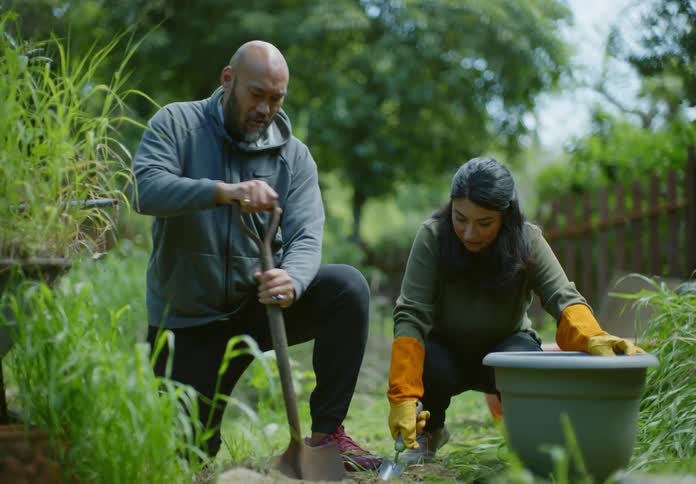 Man and woman with a shovel putting soil in the pot while gardening