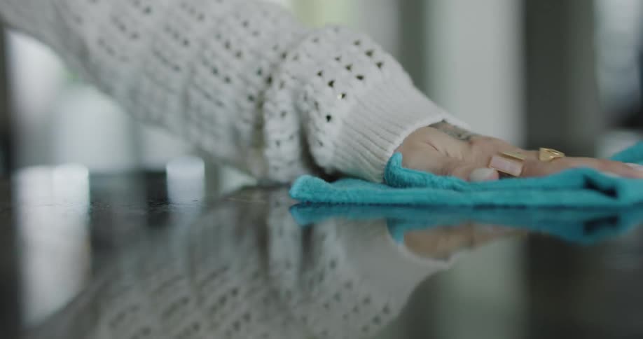 Woman cleans reflective counter with a spray cleaner