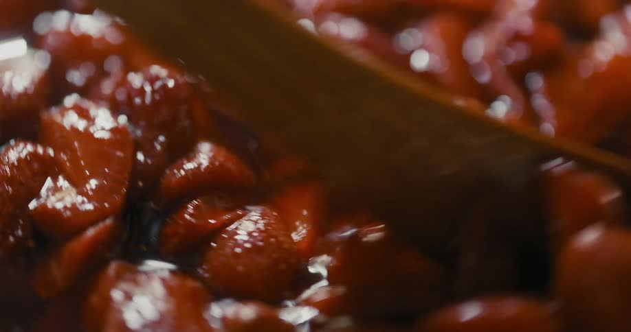 A container of strawberries being stirred