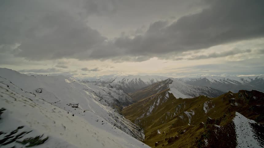 Heavy clouds flow over the snow covered mountains