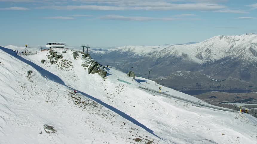 Aerial view of ski lift carries skiers and snowboarders up the snowcapped mountain slope