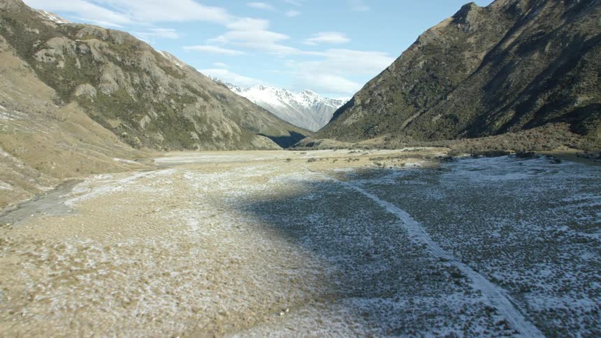 Aerial view of a vast valley with rocky terrain flanked by steep mountains