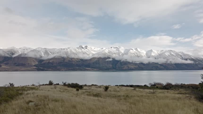 Serene landscape with a large lake and a majestic mountain range in the background