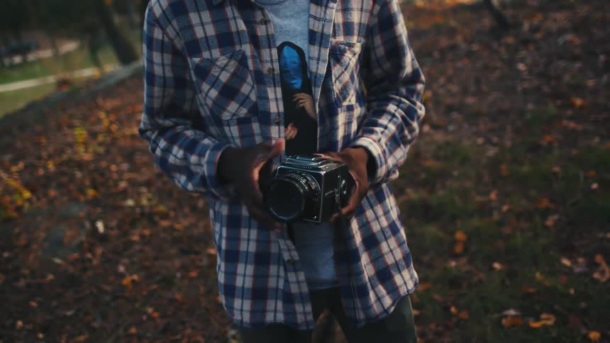 A young man winds film into his vintage camera