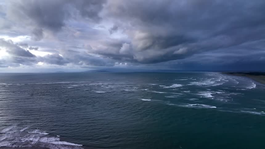 Waves roll onto beach under a vivid dramatic inky sky