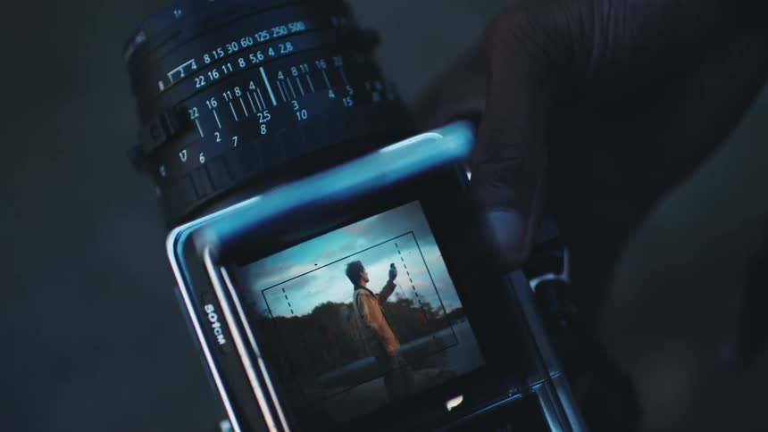 A hand adjusts settings on a film camera