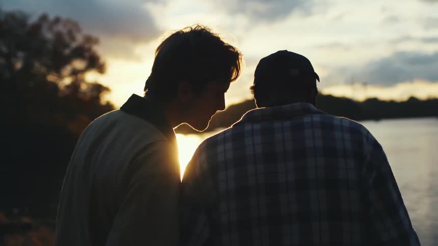 Two friends photograph sunset by a lake