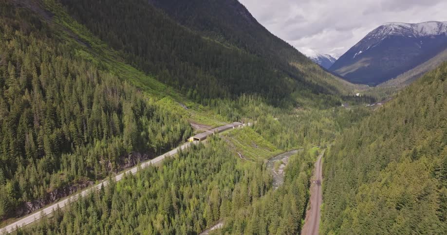 Aerial view of a winding road trough dense forest in the mountains