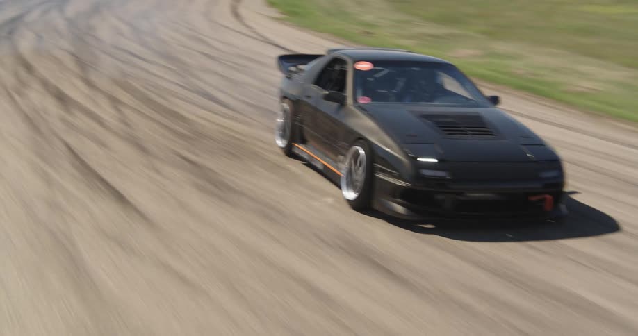 Cars are drifting around the dirt track as they race