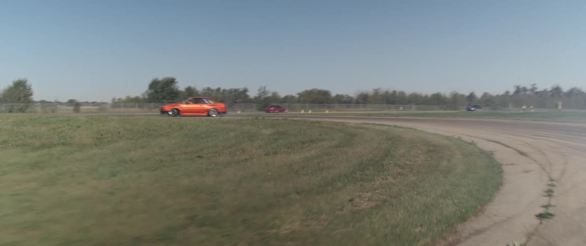 An orange car drifting around curves in a race with other cars