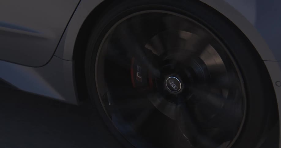 Closeup of a car tire focusing on the moving brake disc and caliper