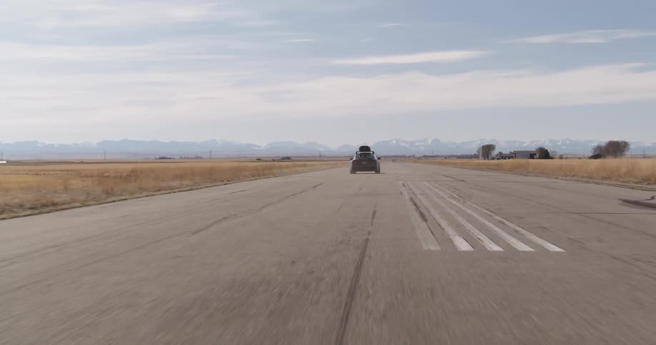 Car moving on a paved road with open fields