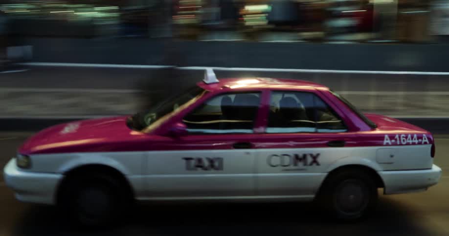 Pink and white mexico city taxi moving through the city