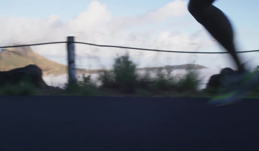 A closeup of a persons lower legs midstride while running on an asphalt road in the mountains