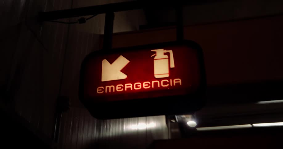 A red illuminated sign with the word emergencia