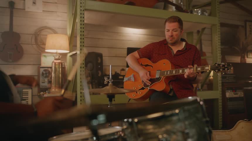 Guitarist and drummer play together in a music room