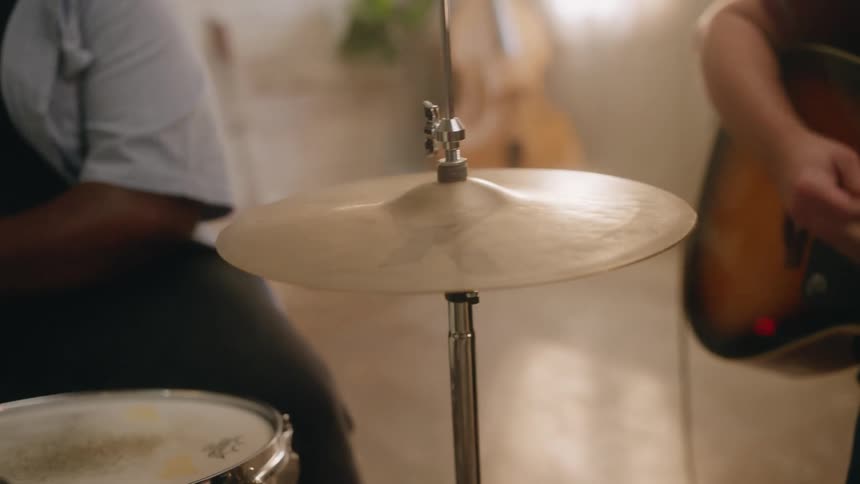 Closeup of a drum cymbal with two people playing next to it