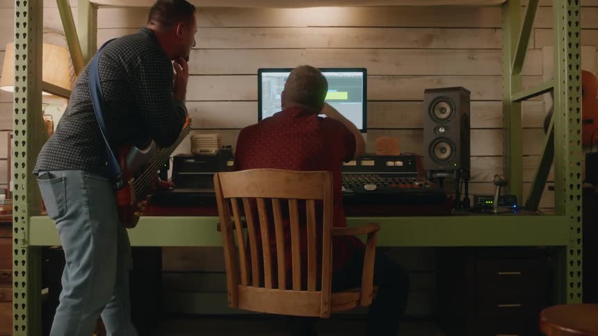 Two men in front of a computer in a music studio environment