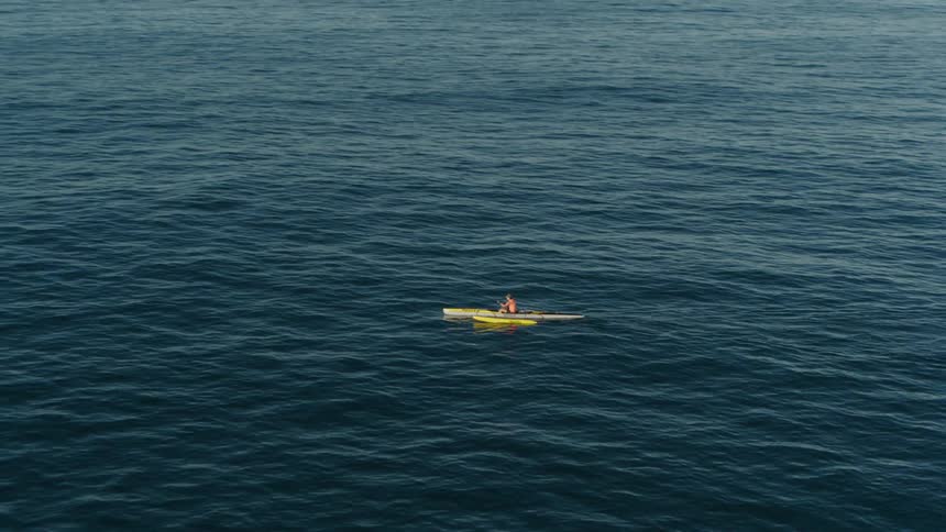 Person kayaking in the middle of a vast blue ocean