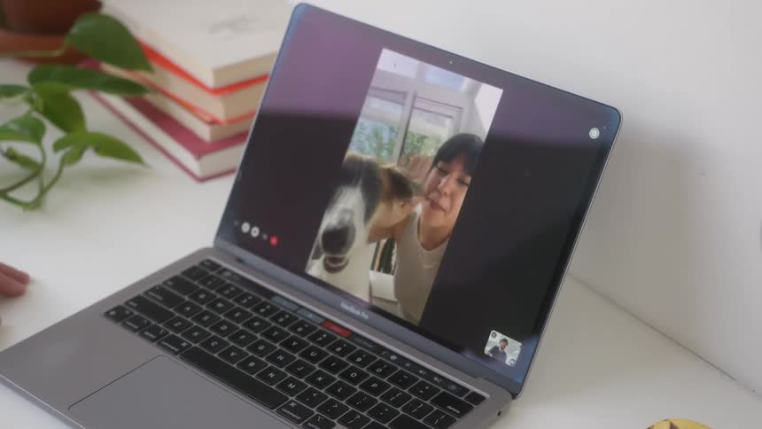 Man has a video call with a woman and a dog on his laptop