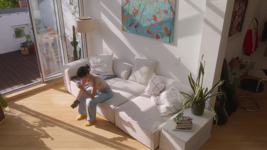 A woman hangs up her phone and lays on the couch