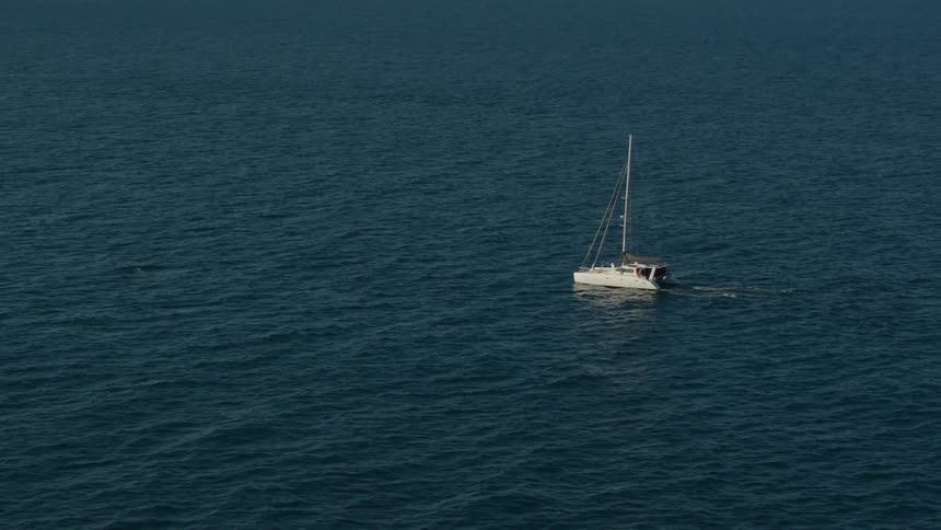 Sailboat uses motor propulsion to move through ocean waters