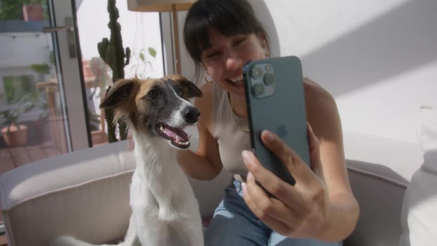 A woman smiles as she takes a selfie with her dog