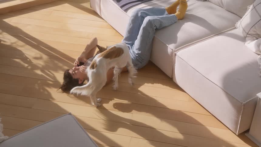 A woman talks on the phone while petting her dog