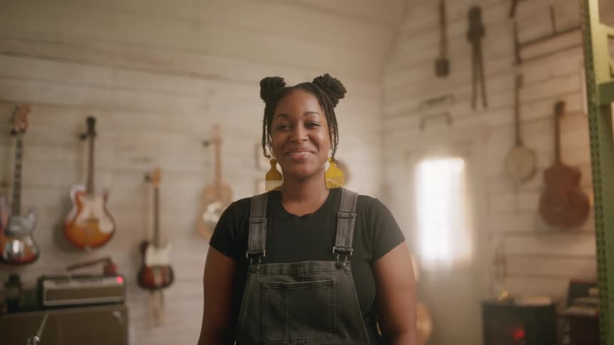 A black female musician smiles in music studio
