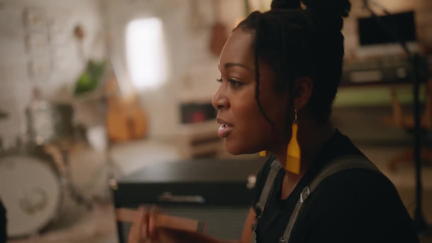 Three musicians sit around a studio singing and playing