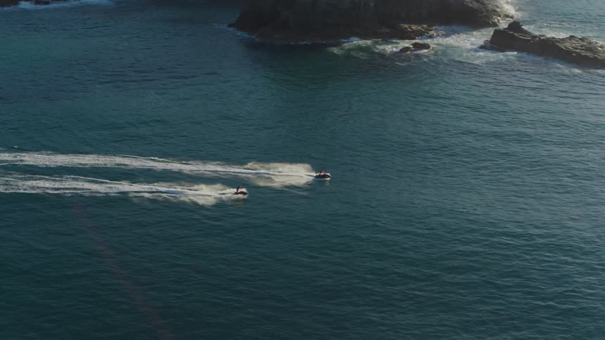Two people ride jet skis in the ocean