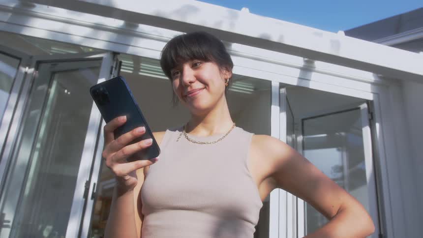 A woman smiles while reading on a smartphone