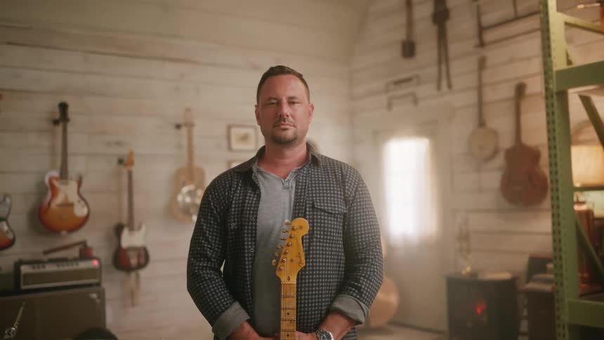 Man in a studio holding a guitar