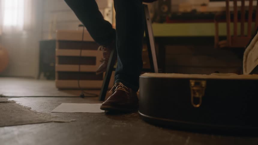 Closeup of a mans feet tapping the floor with a guitar case next to him