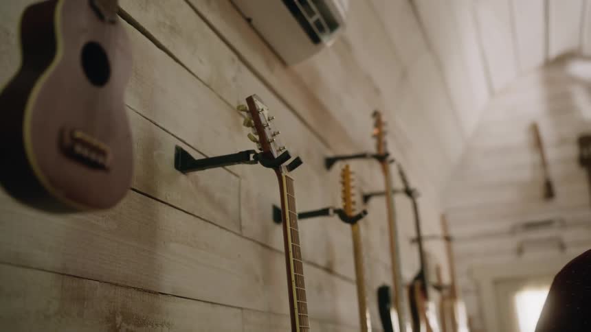 Man hangs guitar on wall with other guitars