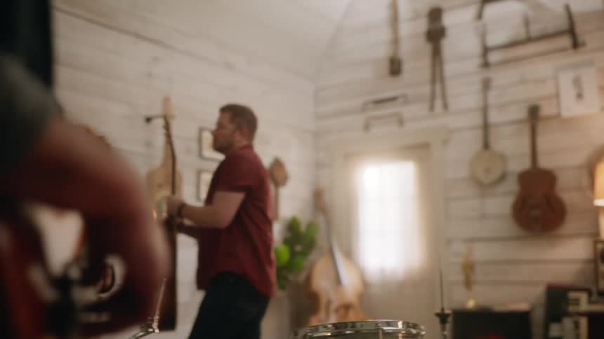 A musician hangs his acoustic guitar on the wall of a room