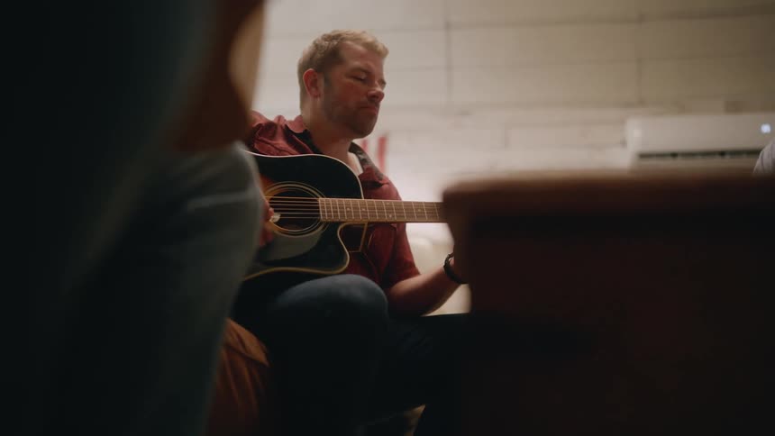 Man sitting in an armchair playing guitar