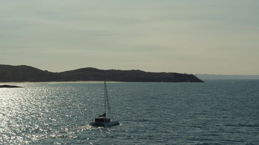Aerial view of a boat sailing across a clear blue ocean off the coast