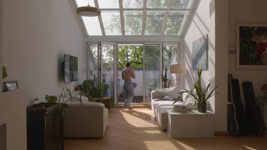 A woman walks through her home while talking to someone via a laptop