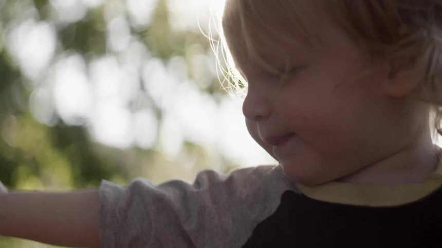 Toddler stretching out an arm with the sun shining brightly behind them