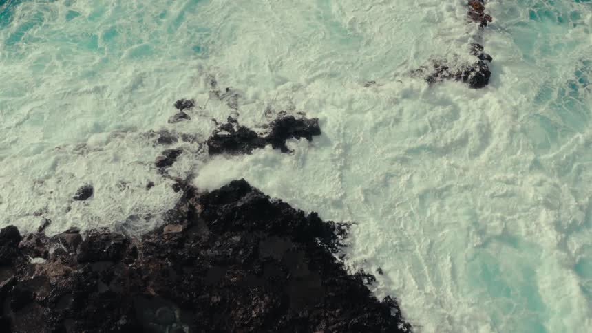Foamy waves crashing on black rocks