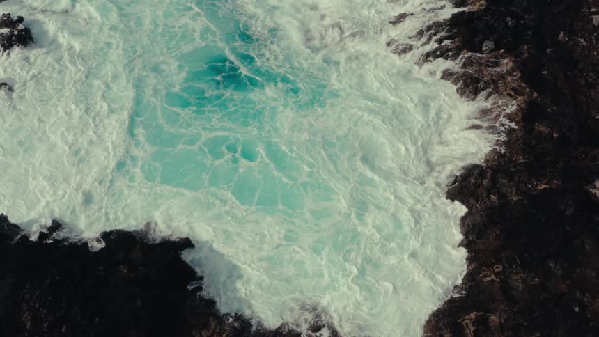 Foamy waves crash against a rocky shoreline