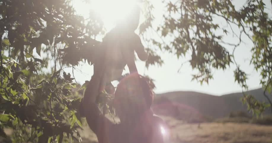 A mother tosses her baby into the air on a sunny fall day