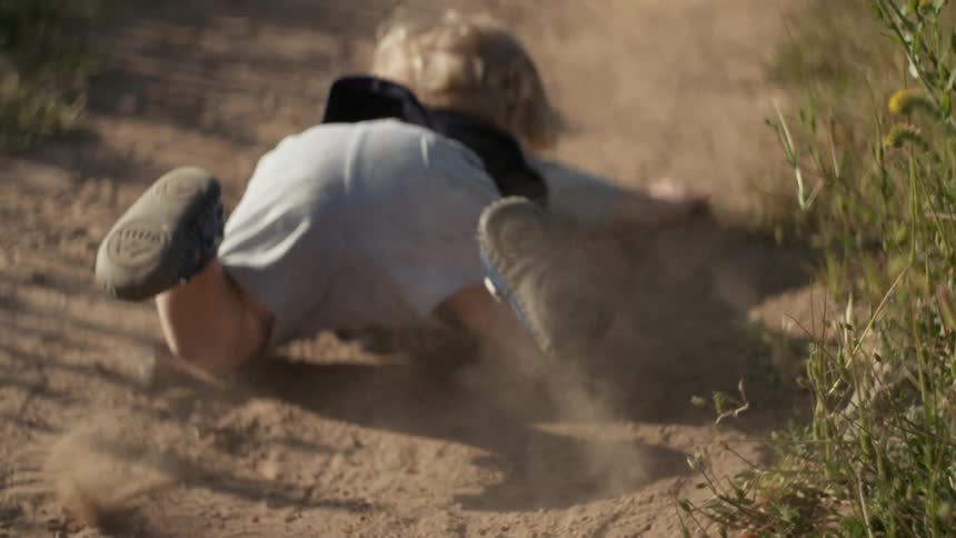 Child running and falling face first onto a dirt path