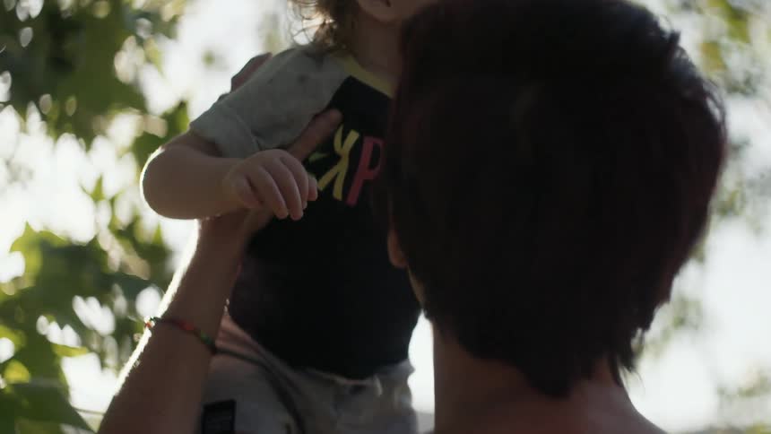 A woman picks up a child under a tree during the day