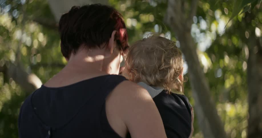 Woman carrying a toddler through some trees