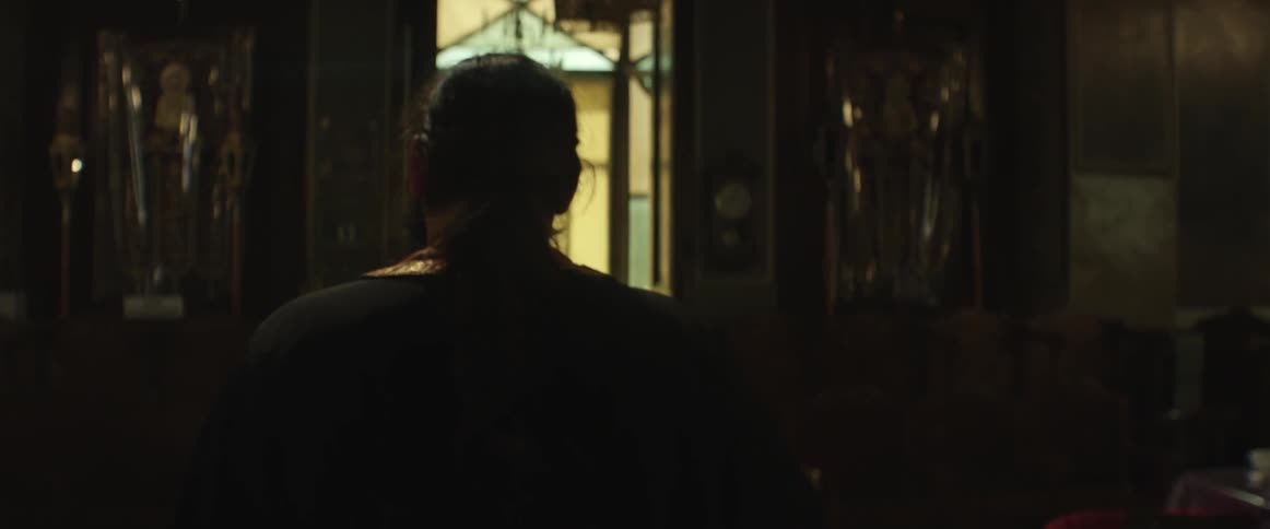 Man with a ponytail walks through a house