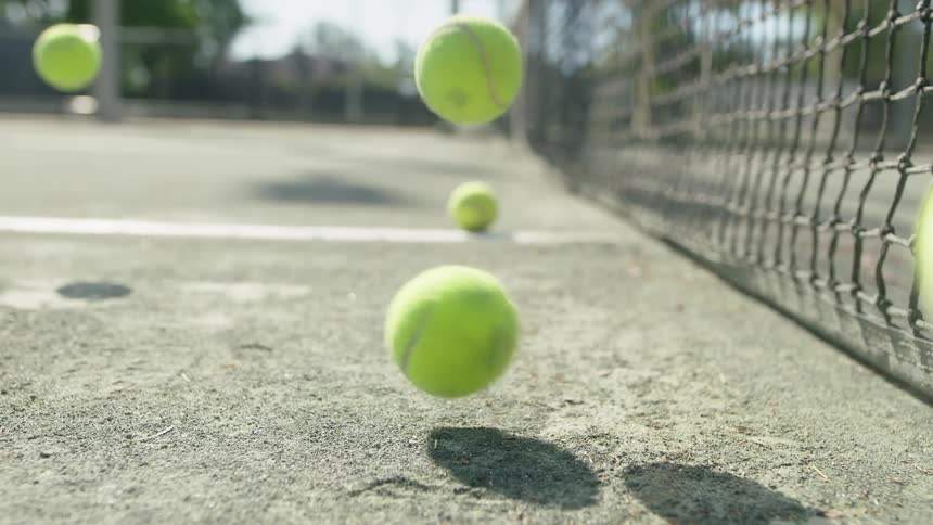 Tennis balls bounce on the court near the net