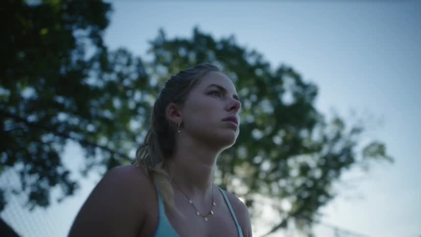 A female tennis player stands ready and focused to receive serve