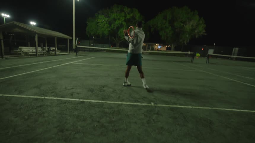A man is playing tennis and hitting the ball using his racket